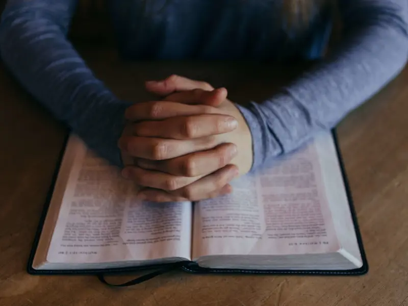 Hands praying over the Bible